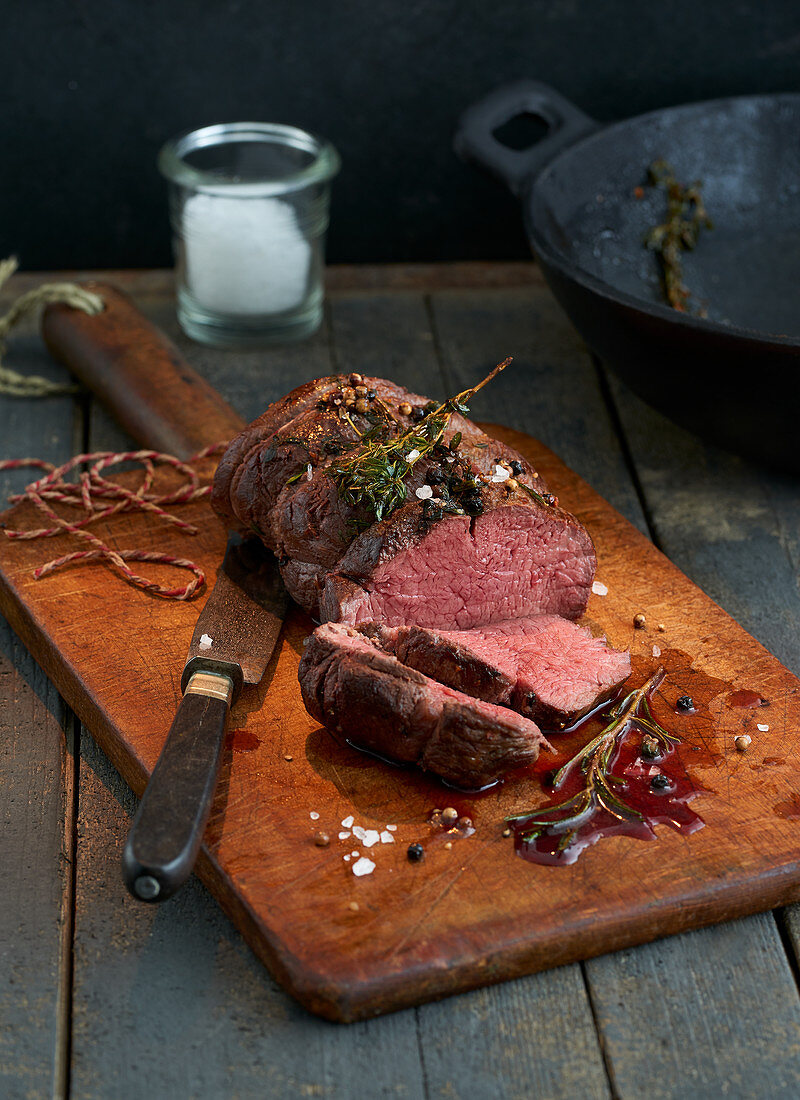 Beef fillet with rosemary on a rustic wooden board