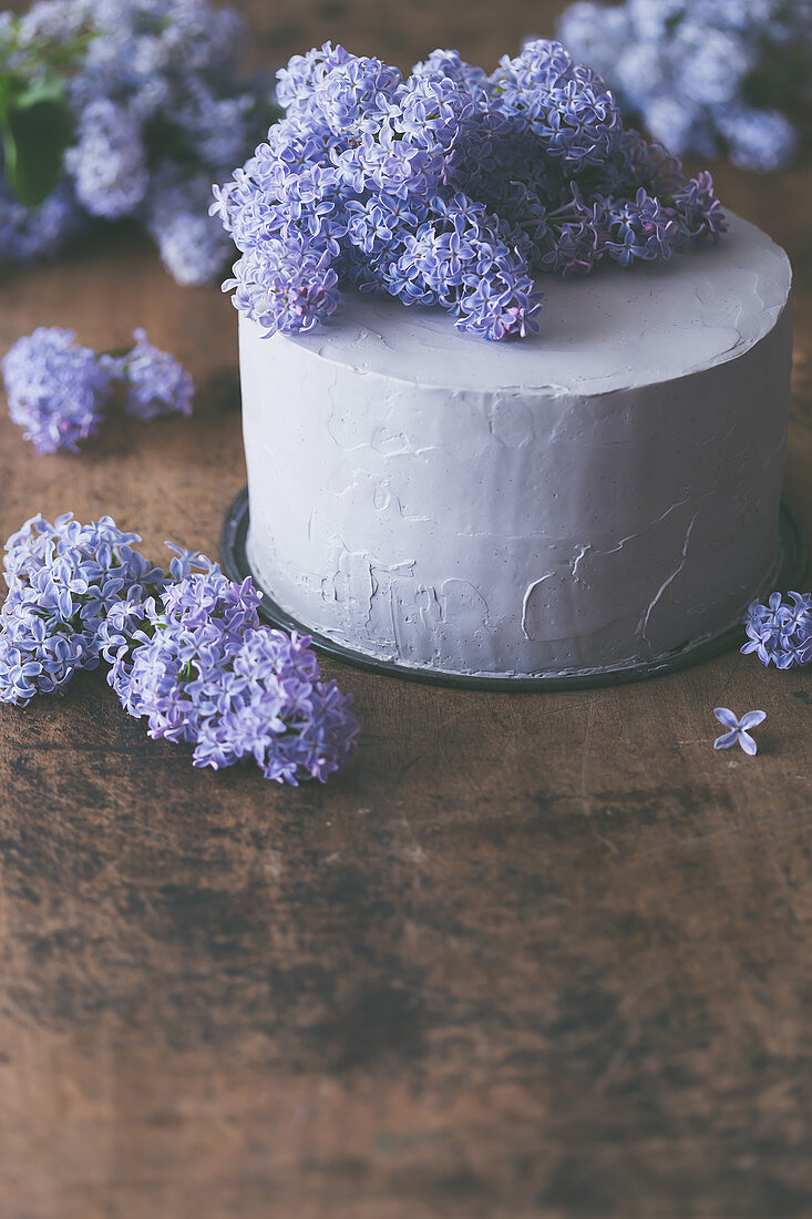 Layer cake with lilac blossom, on a rustic wooden surface