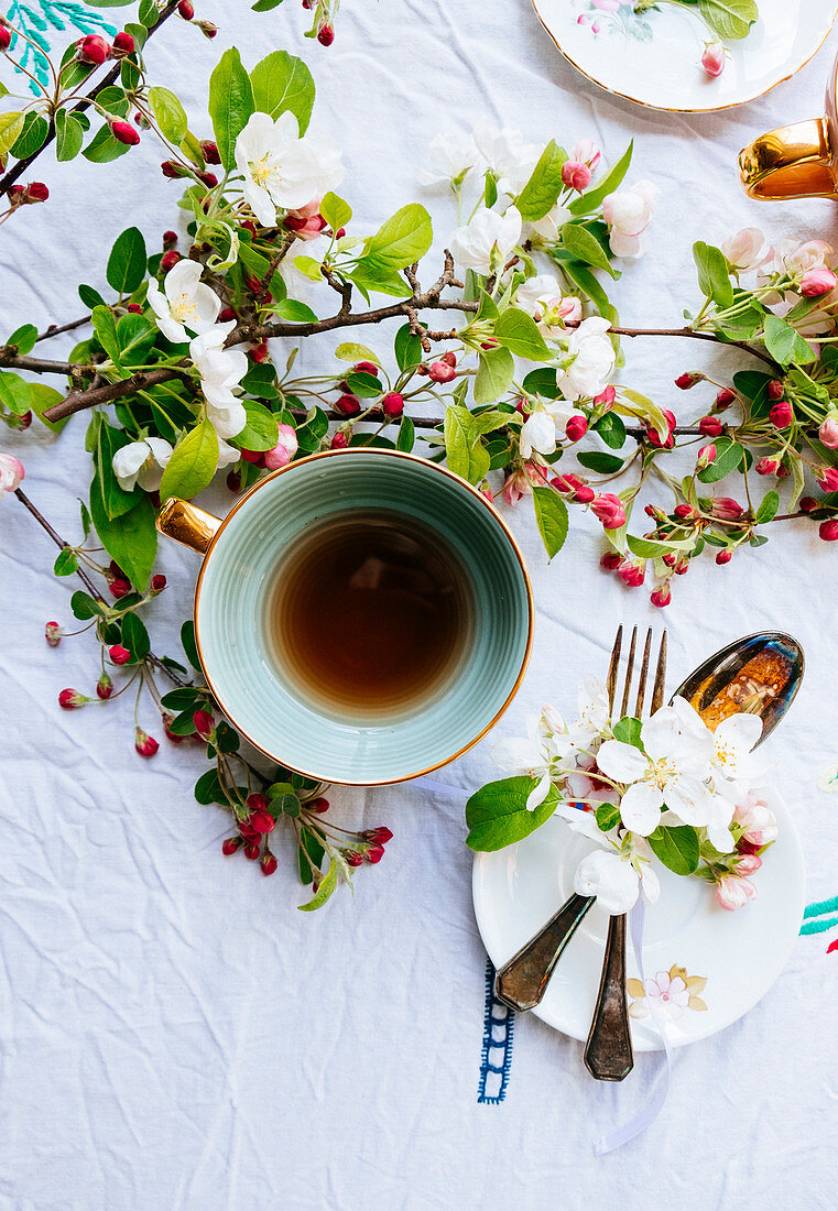 Grüne Teeschale und Blüten auf Tisch