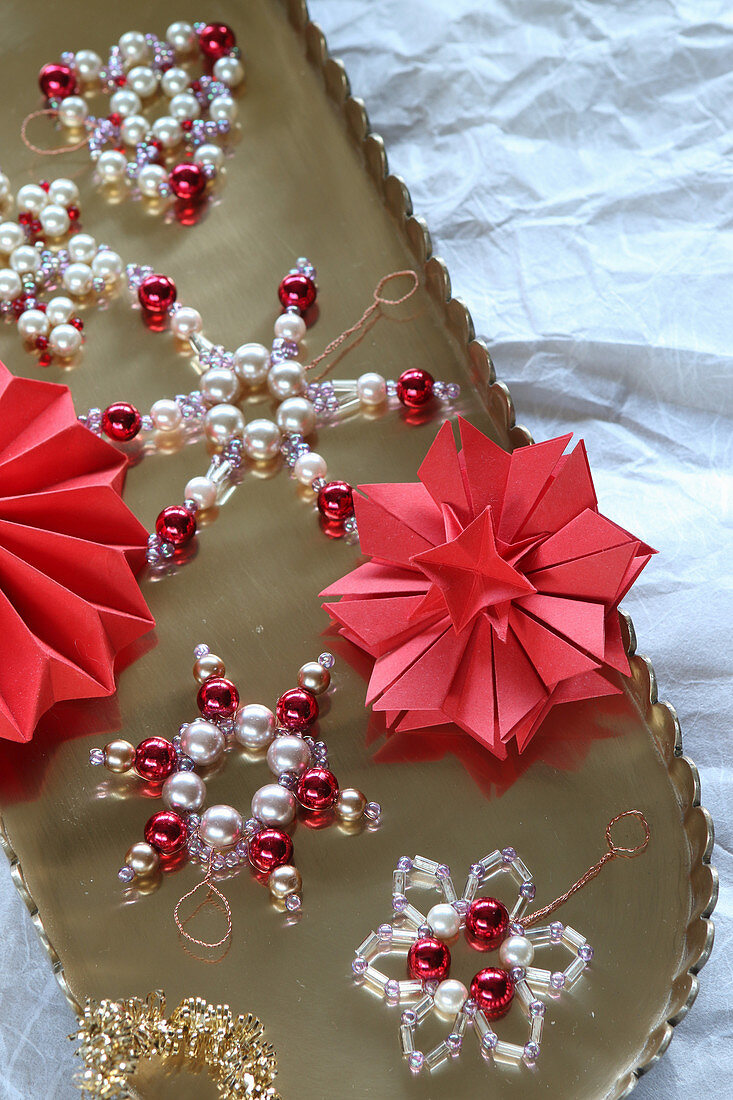 Stars and snowflakes made from beads and folded paper on golden tray