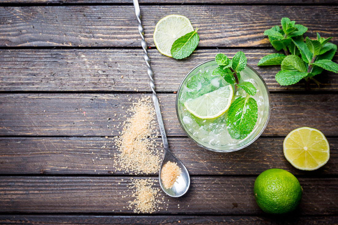 Refreshing mint cocktail mojito with rum and lime, cold drink or beverage with ice on white wooden background