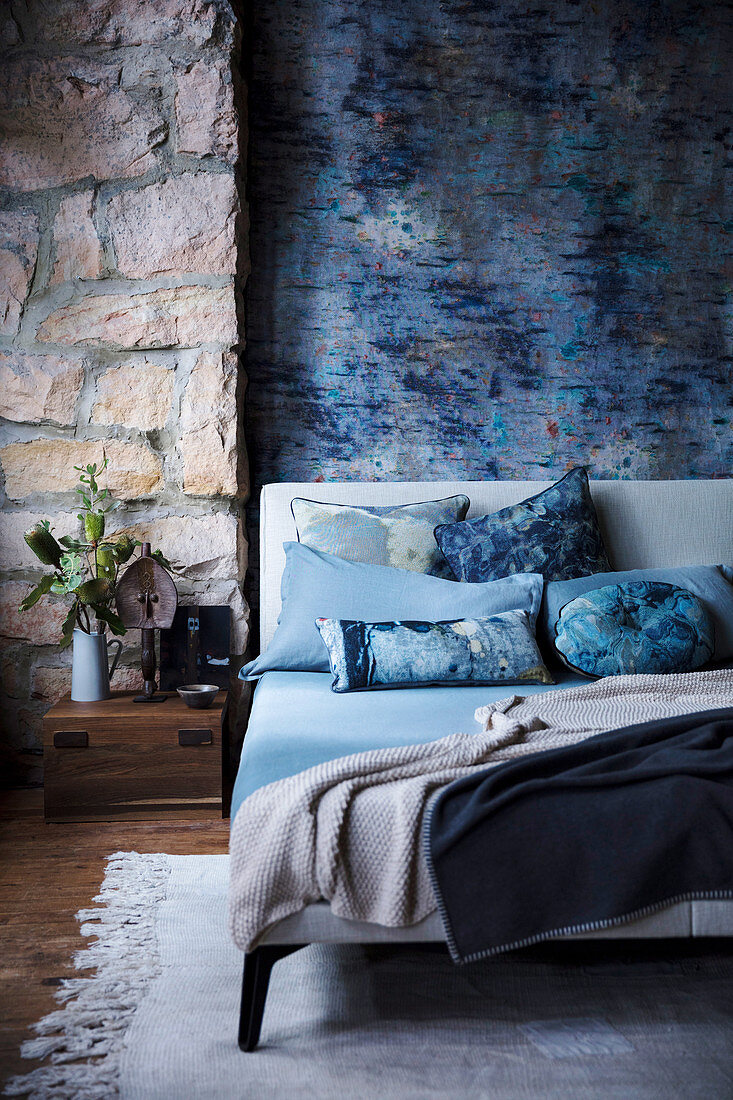 Blau melierte Wand und Natursteinwand im Schlafzimmer