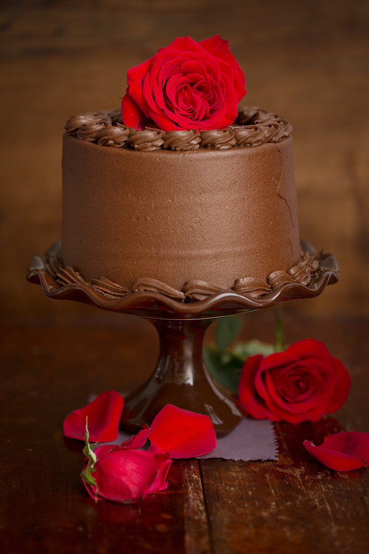 Schokoladencremetorte mit roten Rosen auf Tortenständer