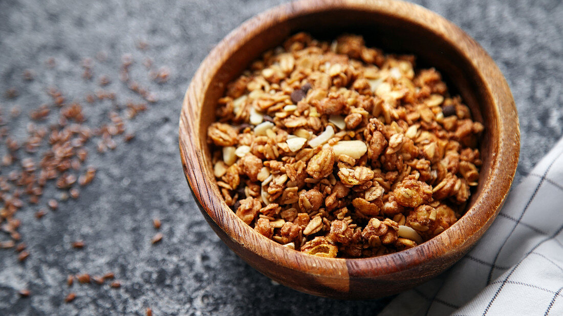 Granola in wooden bowl on gray background