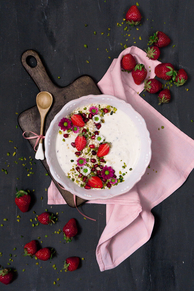 A yoghurt bowl with wholemeal oats, strawberries, pistachios and pomegranate