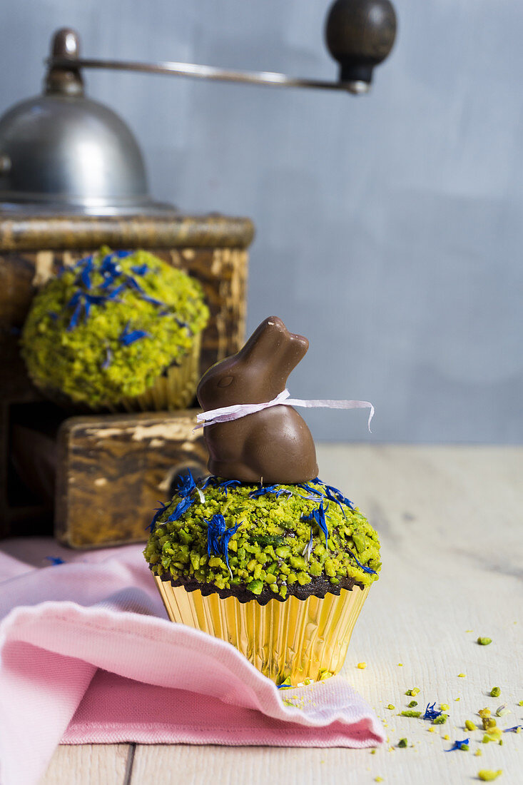 A chocolate muffin topped with chopped pistachios and a chocolate bunny
