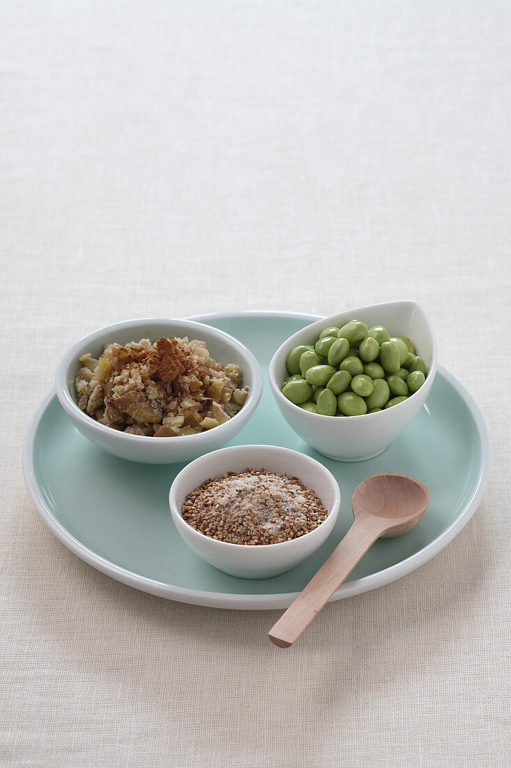 Chestnut cream, sesame seeds, and broad beans in small bowls on a plate