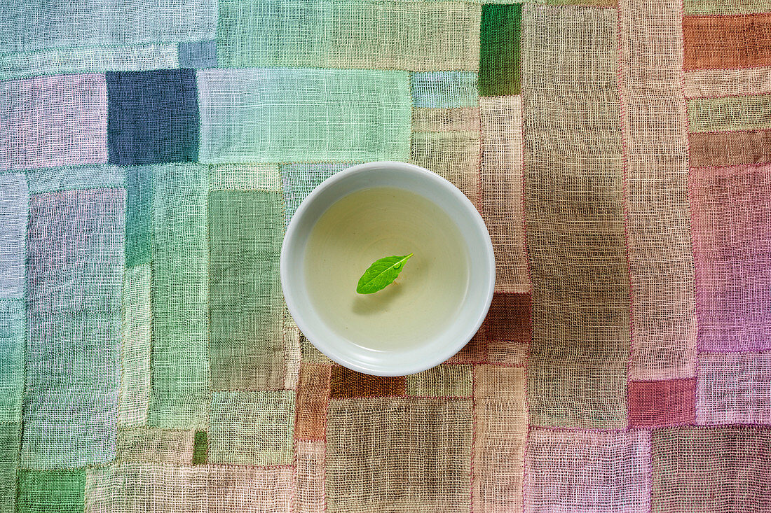 Green tea with a leaf in a small bowl