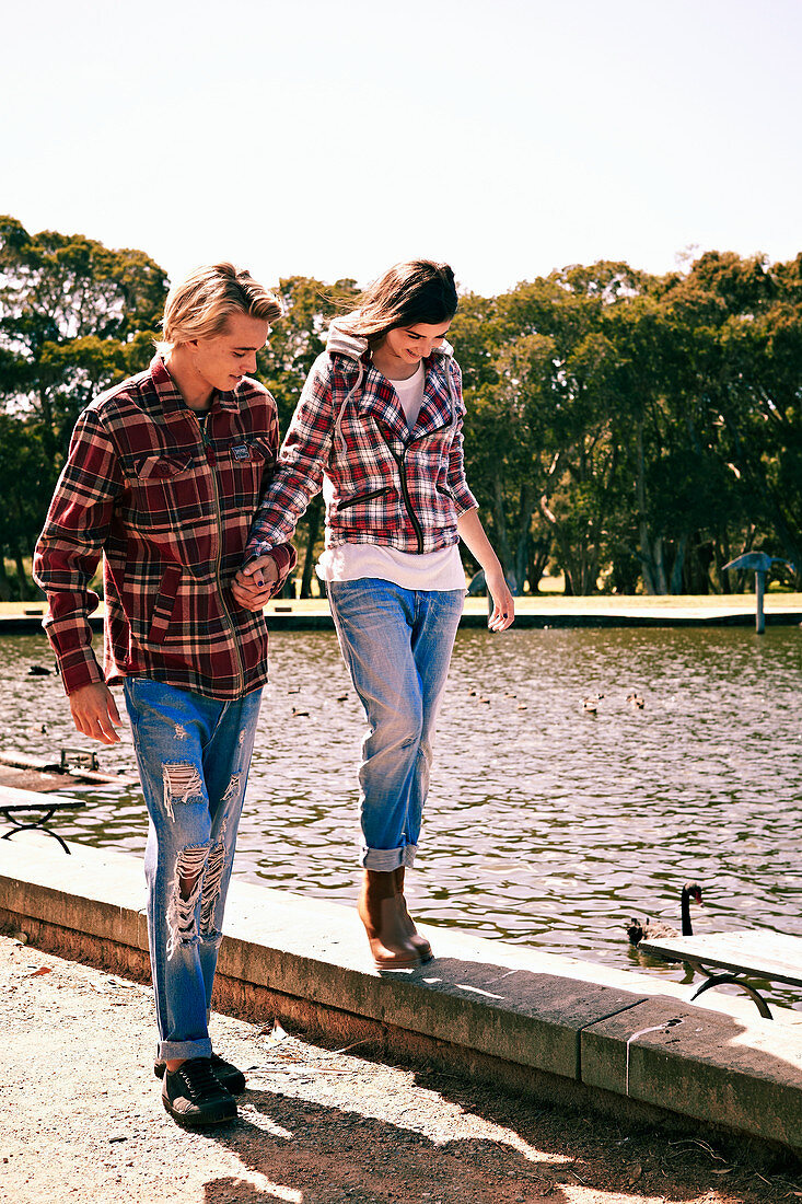 A young couple wearing matching outfits (checked shirts and jeans) by a river