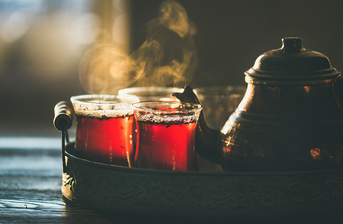Freshly brewed black tea in turkish glasses and teapot in oriental tray