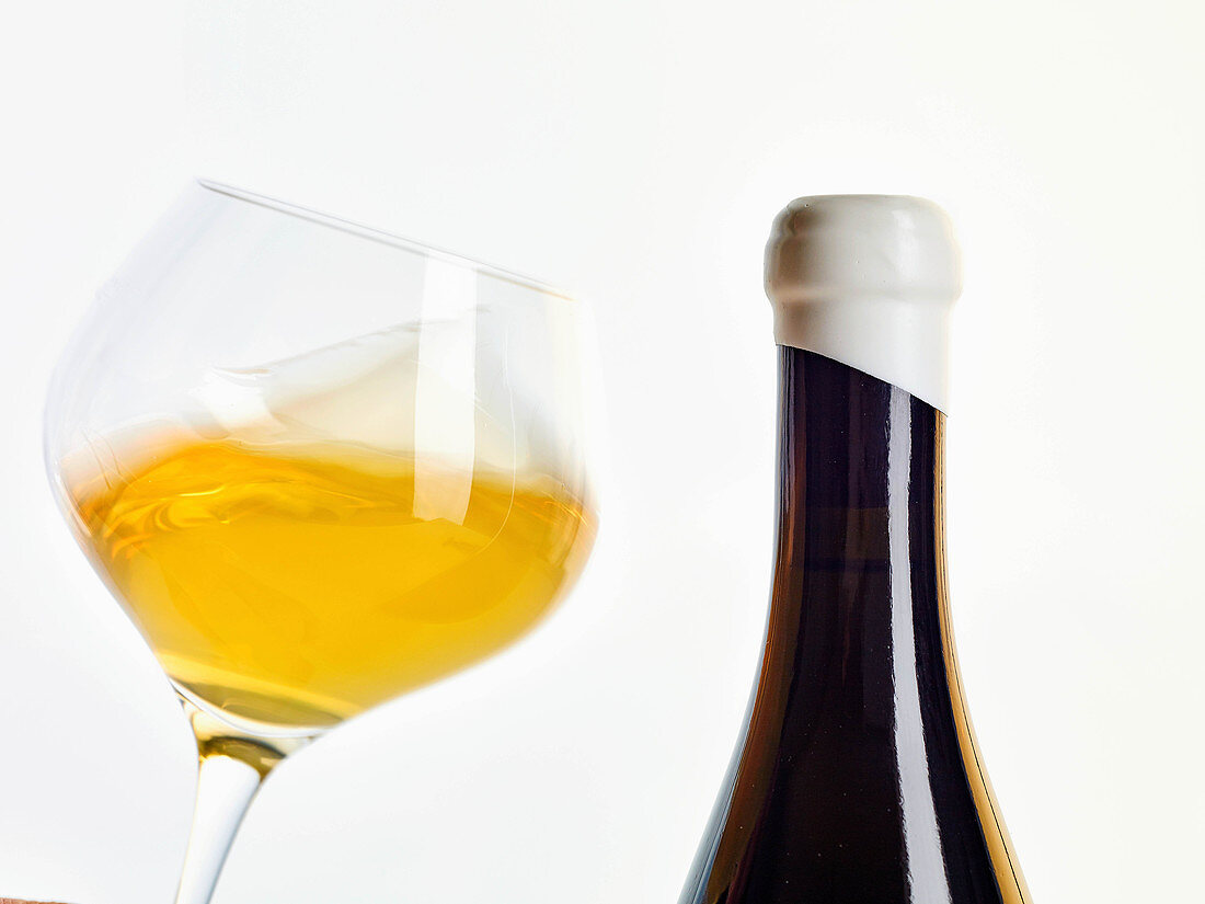 Natural wine in a glass and a bottle (orange wine)