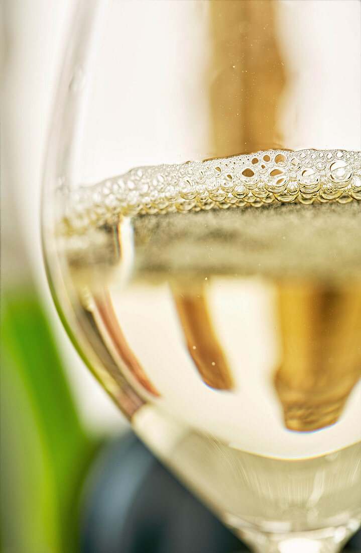 A glass of sparkling wine in front of a bottle