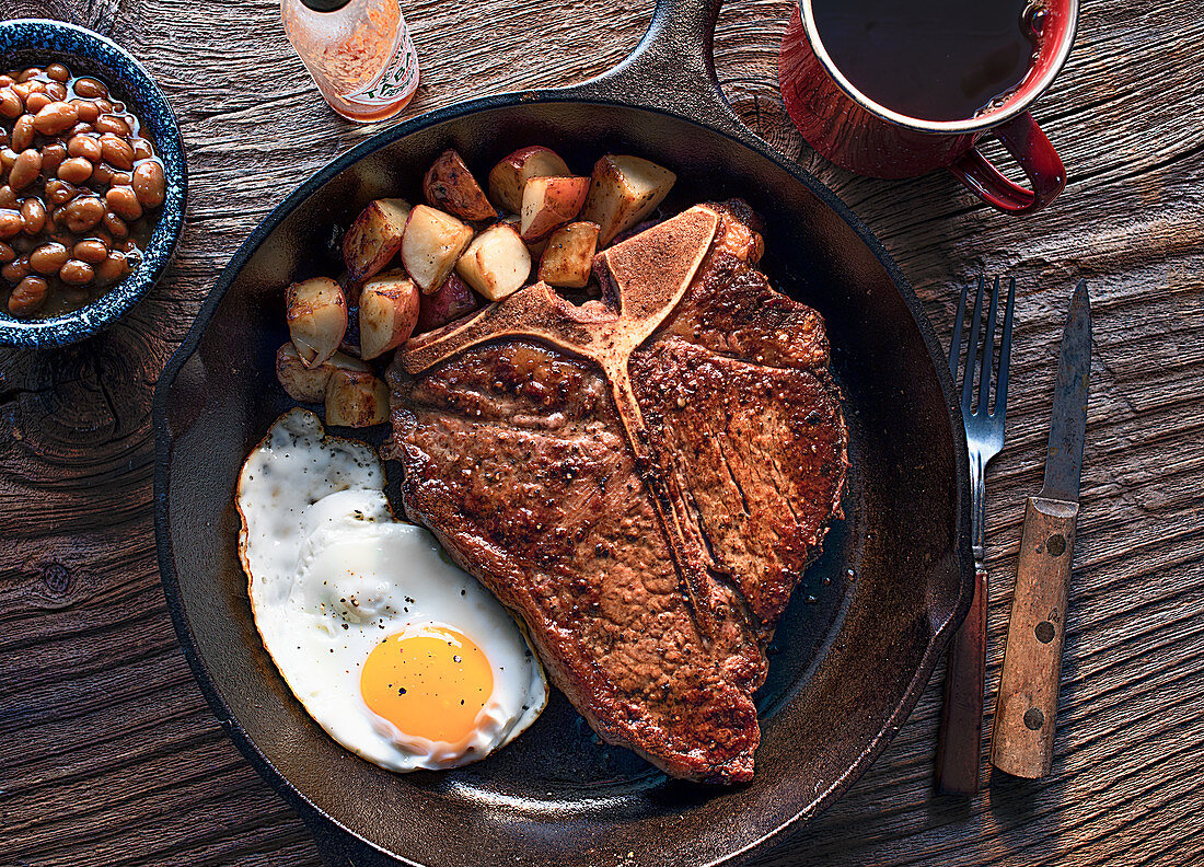 T-bone steak with fried egg and fried potatoes (top view)