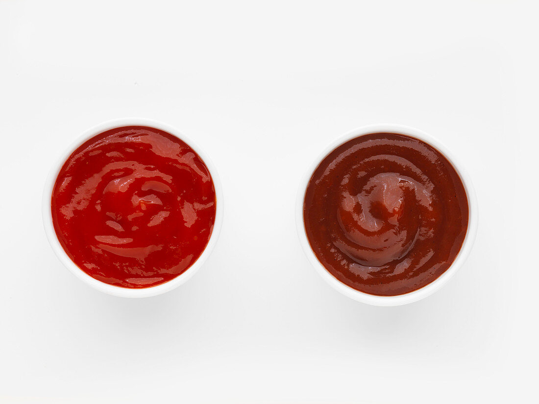 Two bowls of ketchup against a white background (top view)
