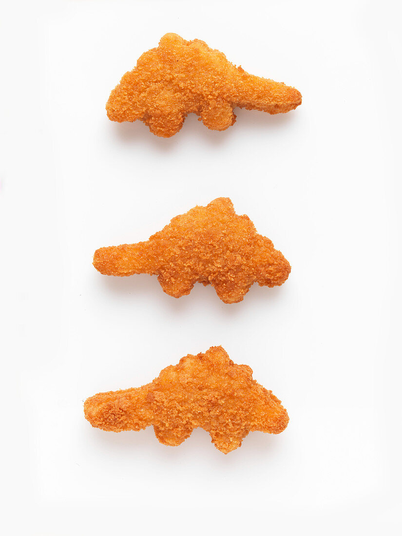 Drei Chicken-Nuggets vor weißem Hintergrund (Aufsicht)