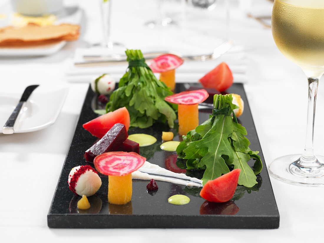 Dekorative Salatplatte mit Rucola, Tomate und verschiedenen Bete-Sorten