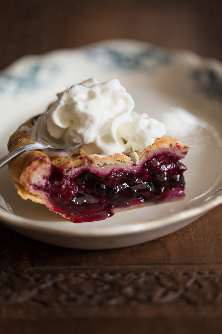 A piece of blueberry pie with cream