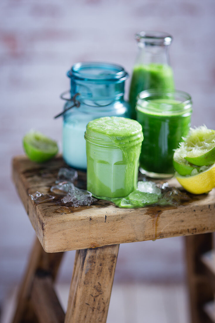 Green smoothies with ingredients on a wooden stool