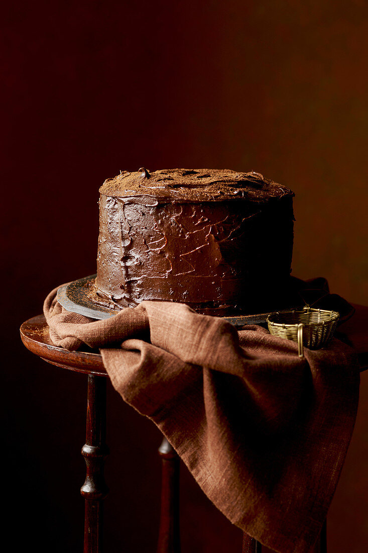 Glutenfreier Schokoladenkuchen auf Beistelltischchen vor braunem Hintergrund
