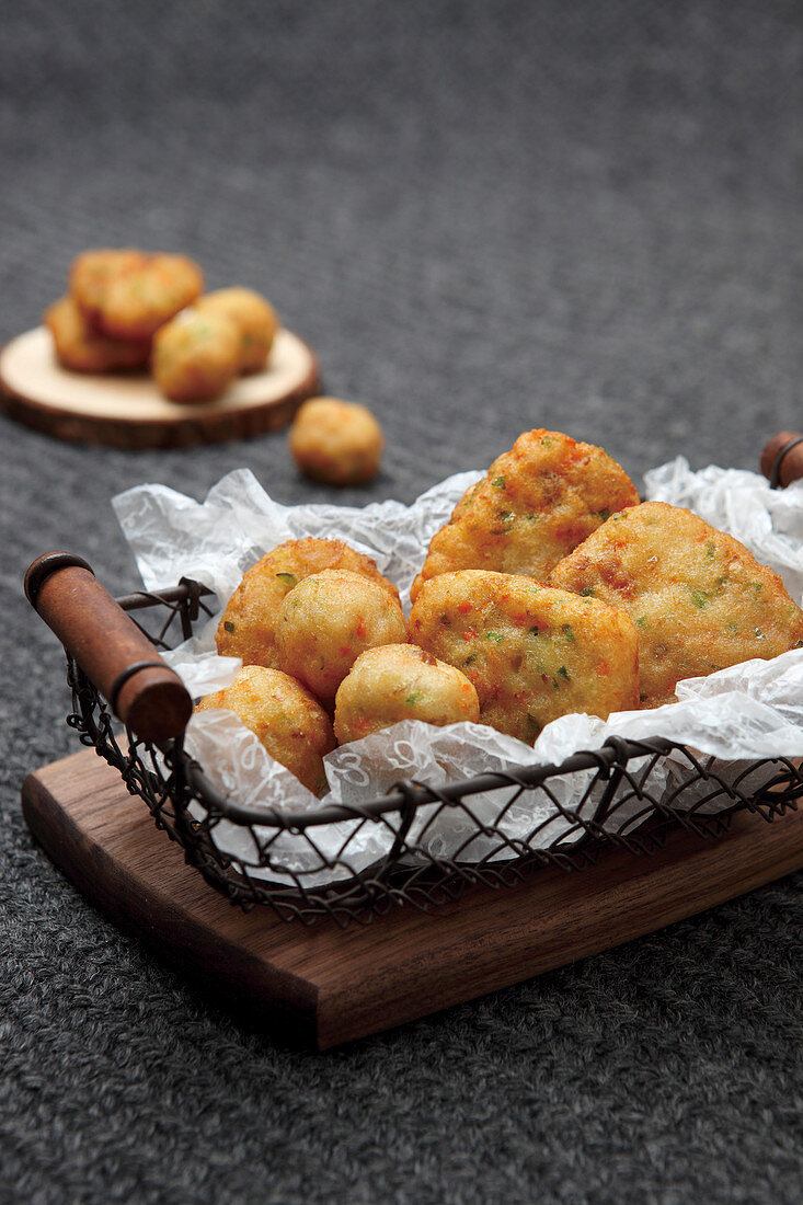 Frittierte Fischbällchen und Fischpuffer in Drahtkörbchen (Asien)