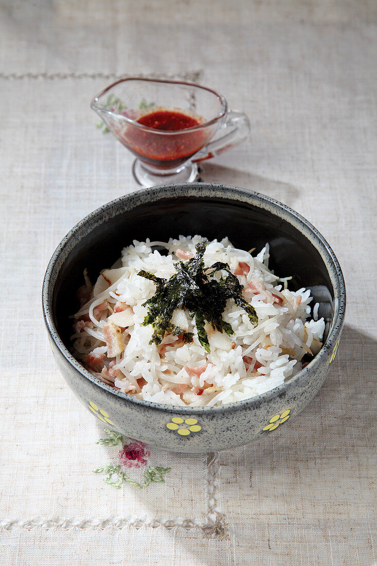 A bowl of rice with bacon, bean sprouts and wakame