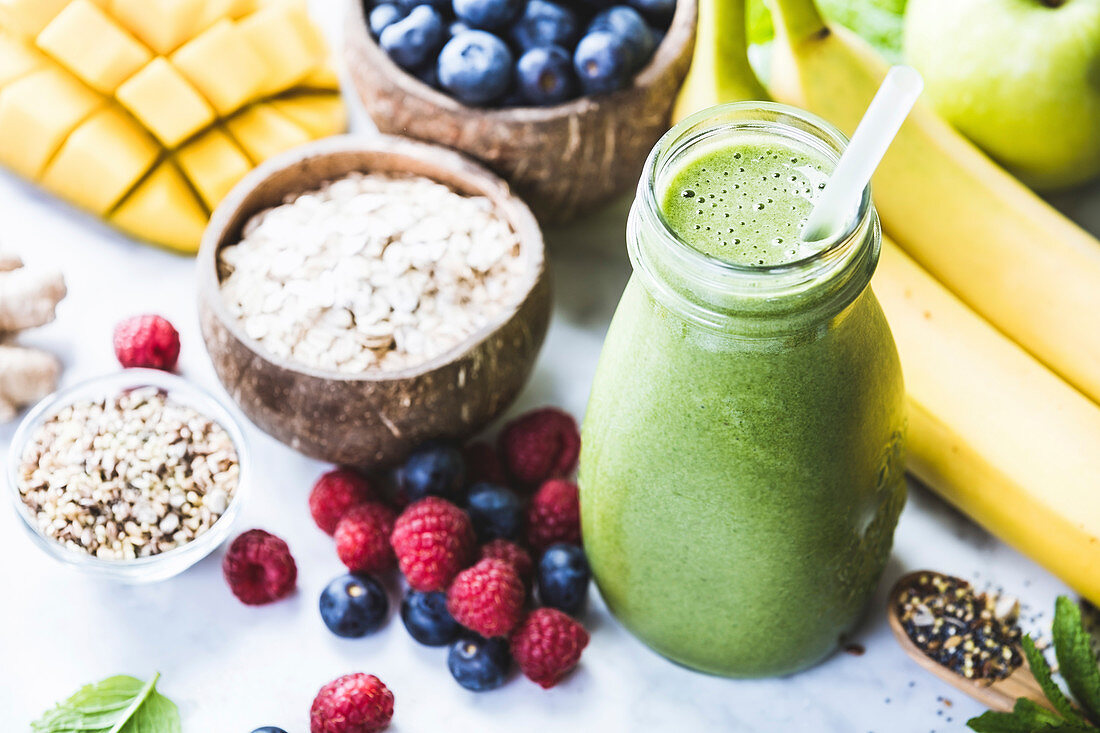 Close-up of green fresh smoothie with fruits, berries, oats and seeds, selective focus