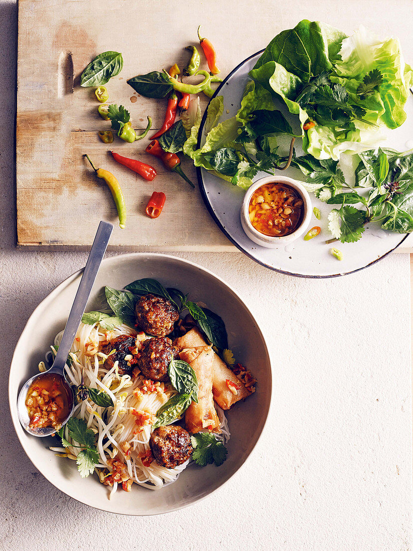 Vietnamese noodles with meatballs, spring rolls and herbs