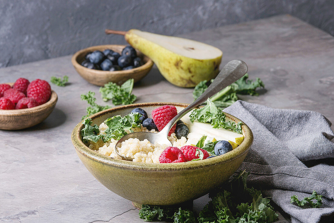 Vegan quinoa porridge with kale, strawberries, blueberries and sliced pear