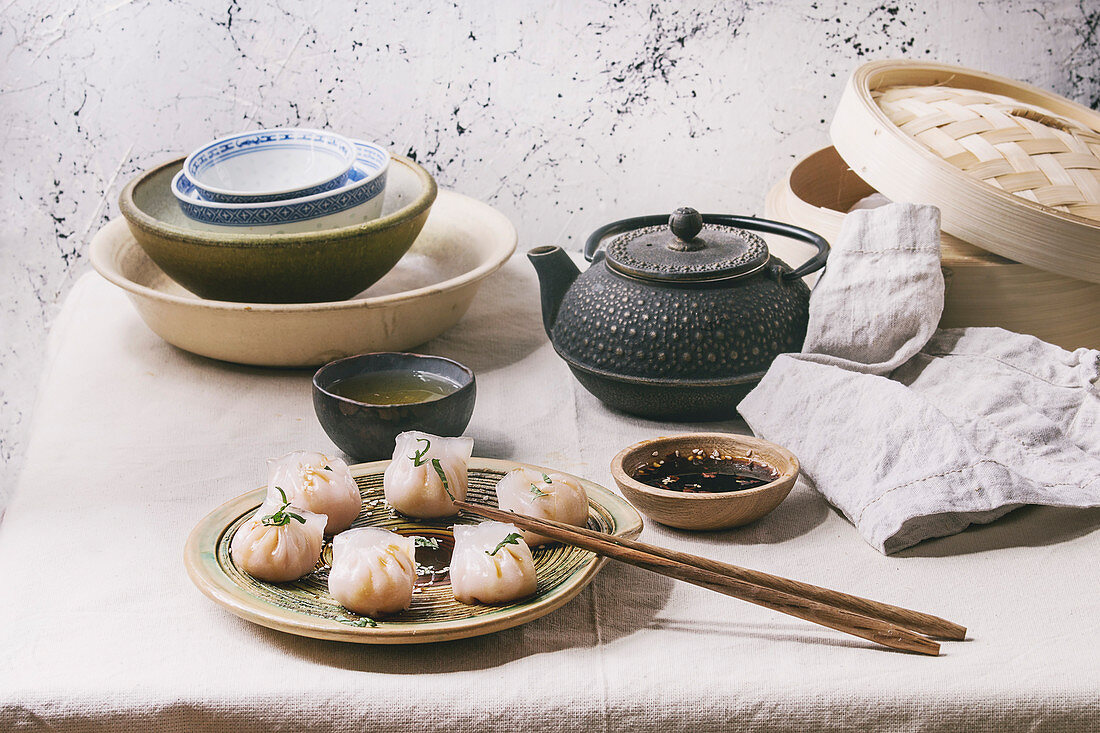 Garnelen-Potstickers auf asiatisch gedecktem Tisch mit Schalen, Teekanne und Dampfkorb (Asien)