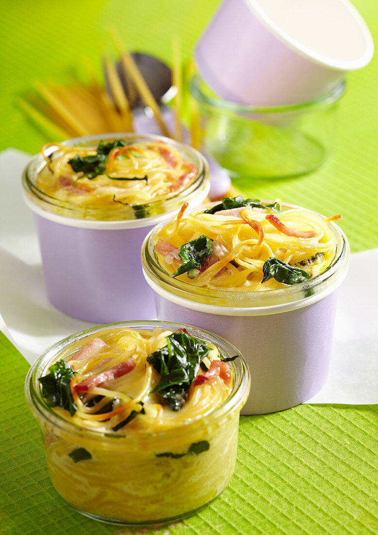 Colourful baked pasta nest with spinach, boiled ham and Parmesan