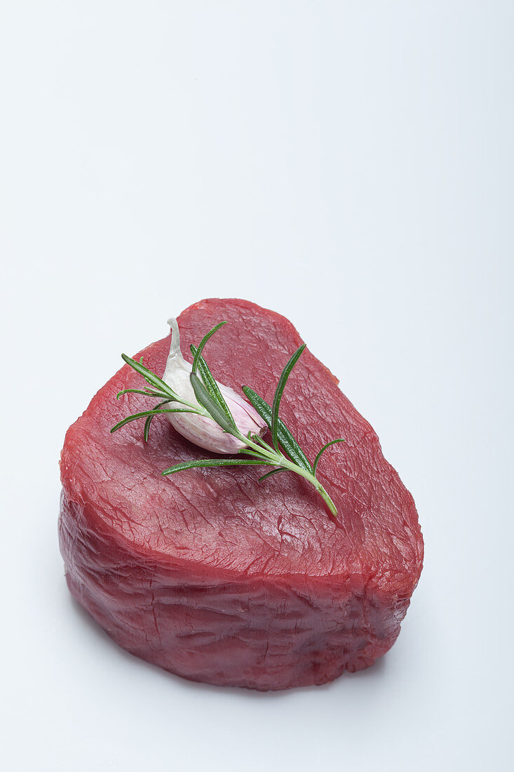 A raw fillet of beef with garlic and rosemary