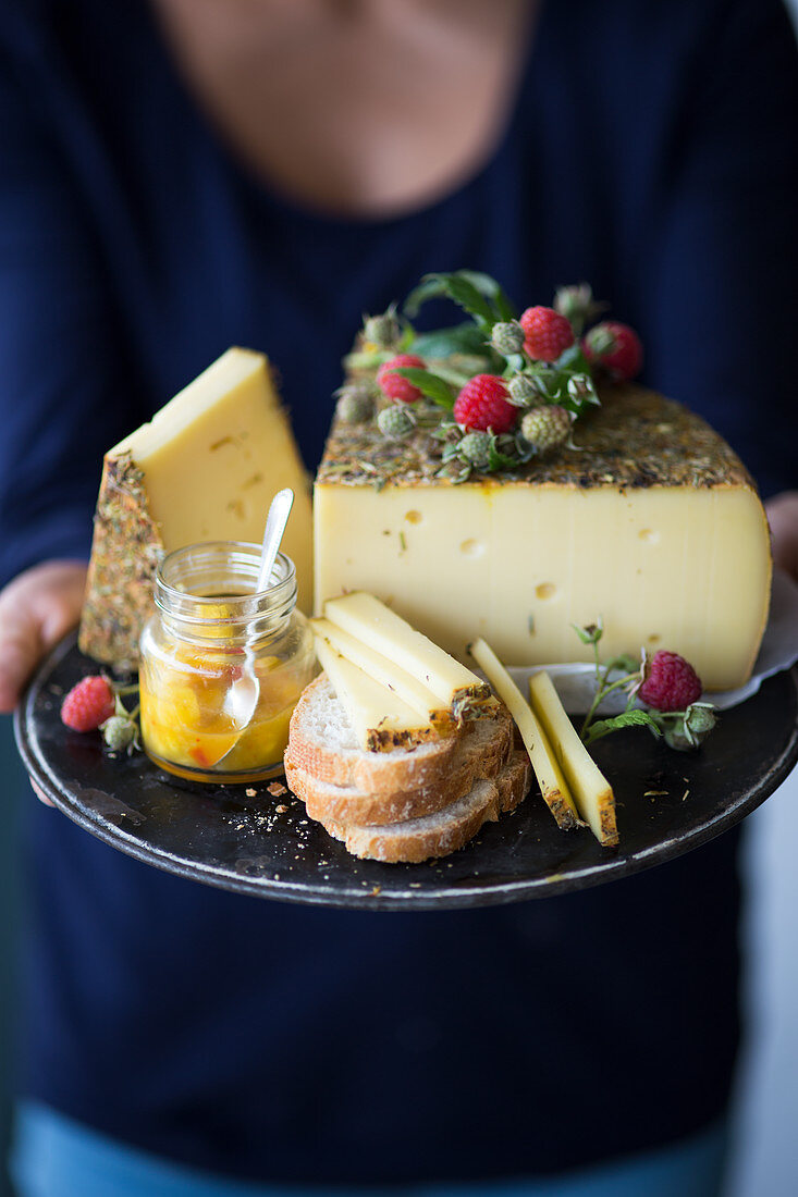 A woman holding a tray of wild herb cheese, bread and chutney