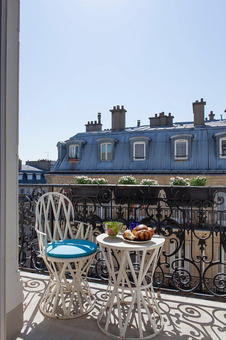 Tisch und Stuhl auf dem sonnigen Balkon in Paris