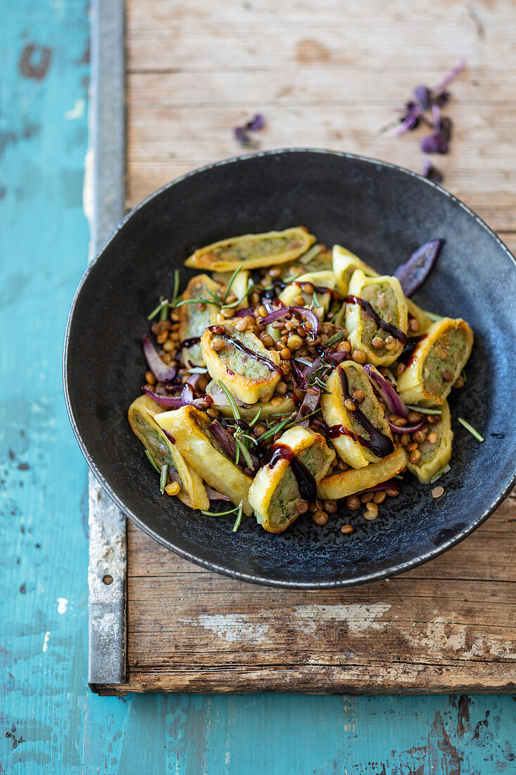 German Raviolis with lentils and red onions in a pan