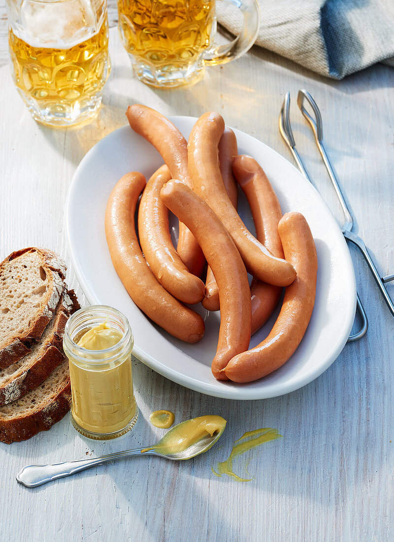 Sausages with beer tankards, a jar of mustard and bread