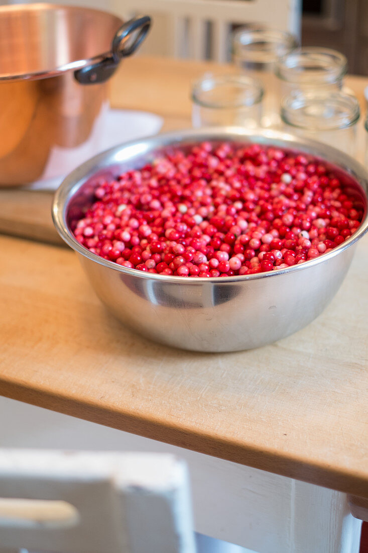 Lingon berry jam being made, raw lingon berries in a bowl
