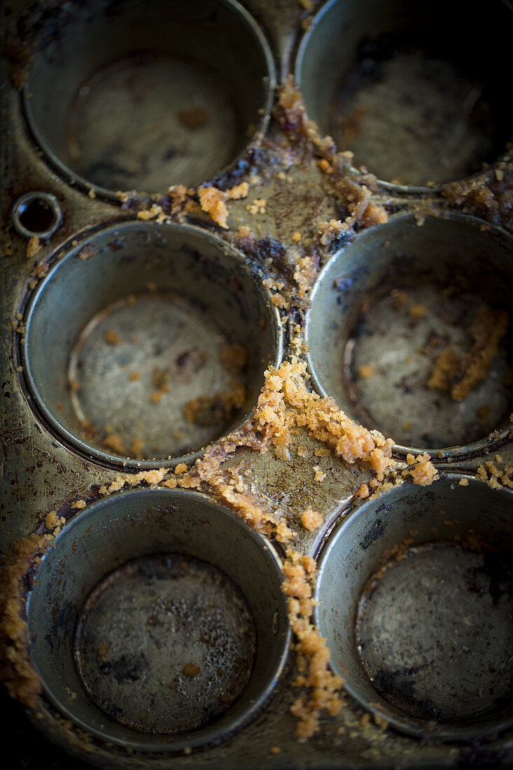 An empty muffin tins with cake crumbs