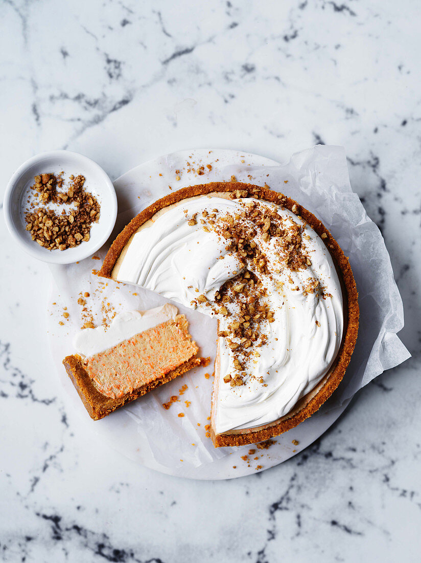 Raw carrot cake topped with cream and chopped walnuts