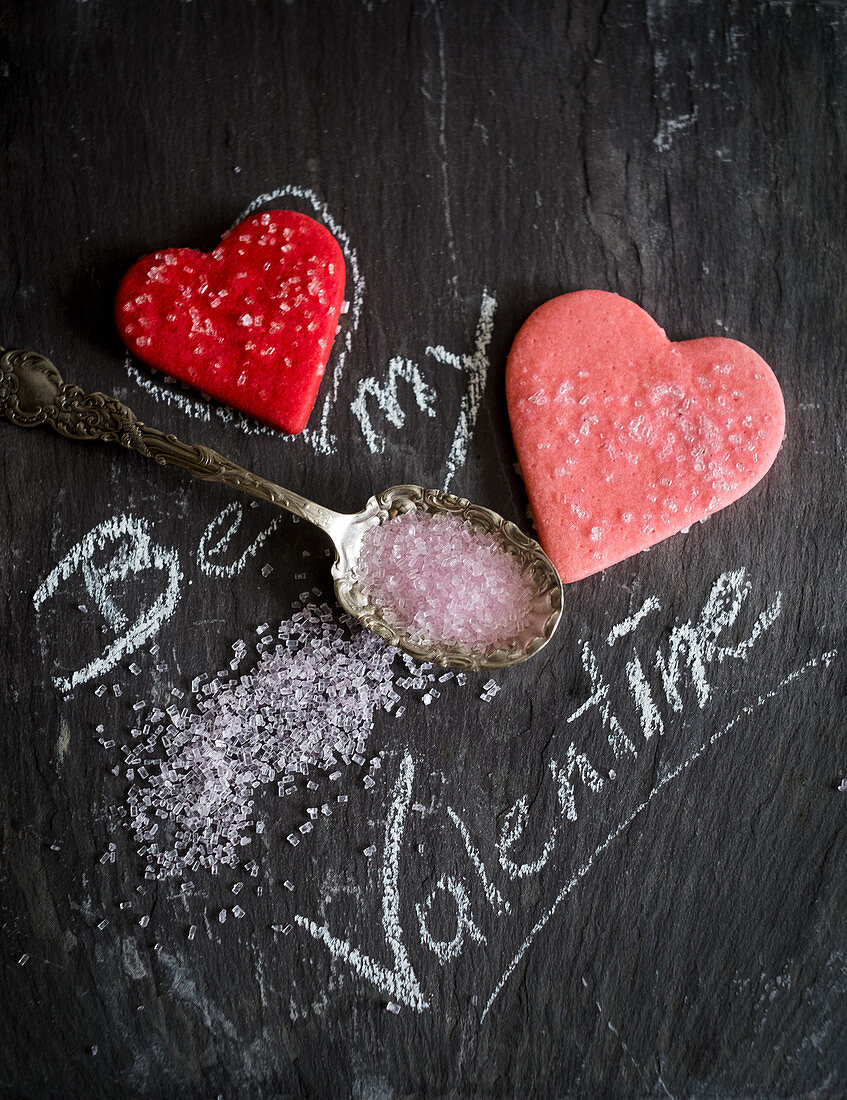 Kreideschrift 'Be my Valentine' mit Herzplätzchen und rosa Zucker