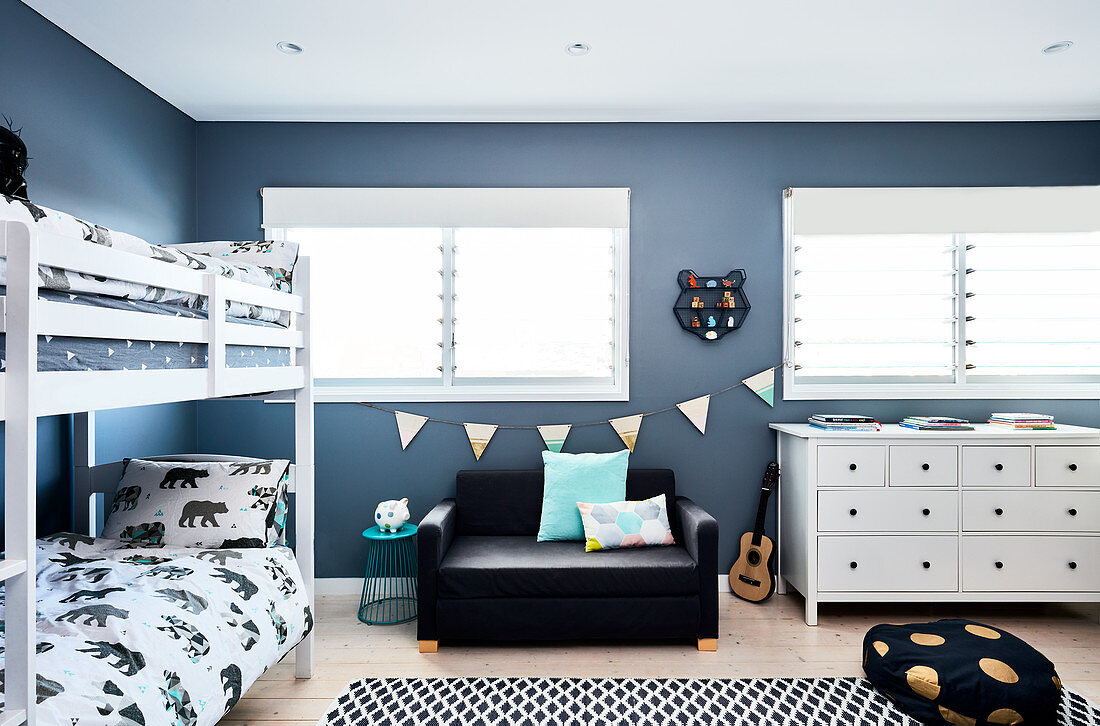 Stockbett, Couch und weiße Apothekerkommode in Zimmer mit blauen Wänden