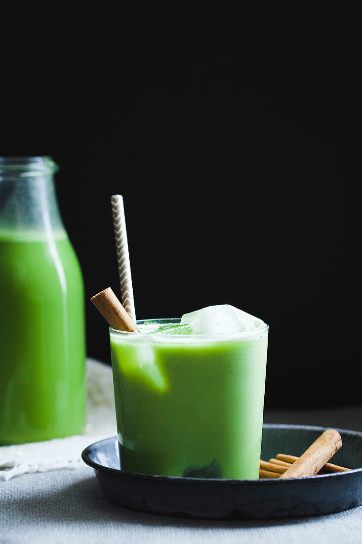 Grüner Matcha-Drink mit Zimt in Glas und Flasche