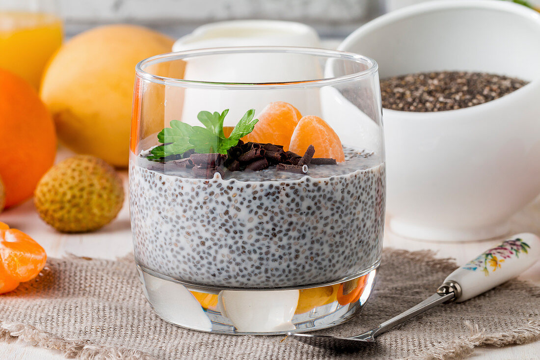 Chia seed pudding with mangoes and tangerines on glass cup for breakfast on white background