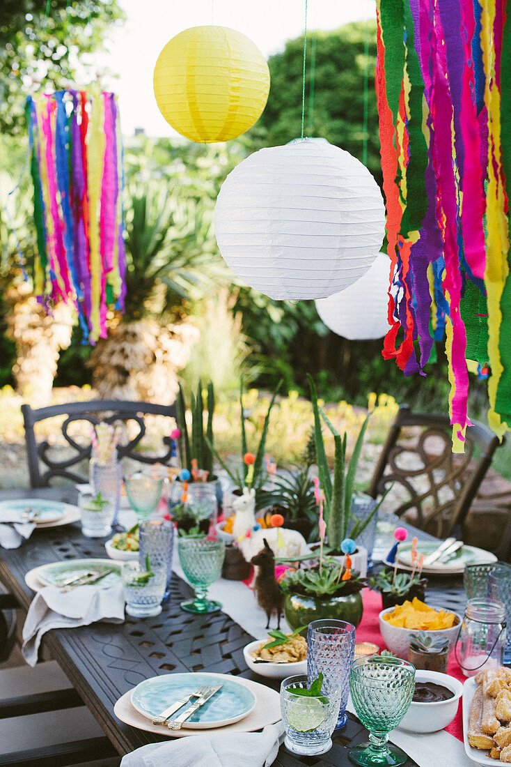 Lanterns above table set in bright colours for Mexican party