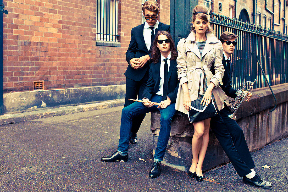 Elegantly dressed young people with musical instruments on the street