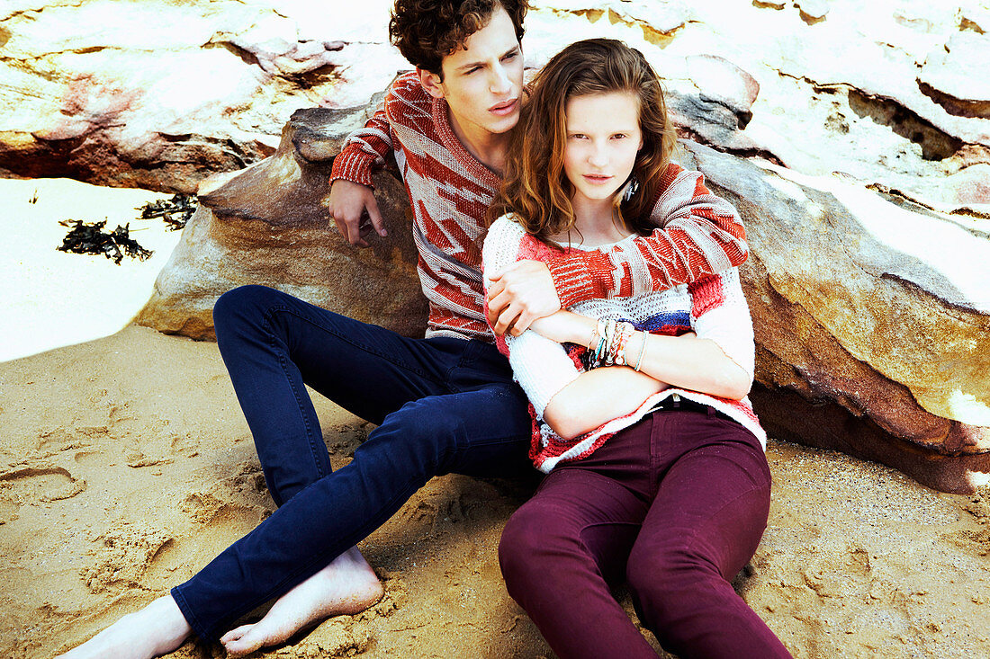 A young couple wearing autumnal outfits on a beach