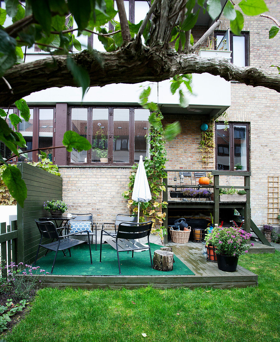 Green rug and seating on wooden deck in garden