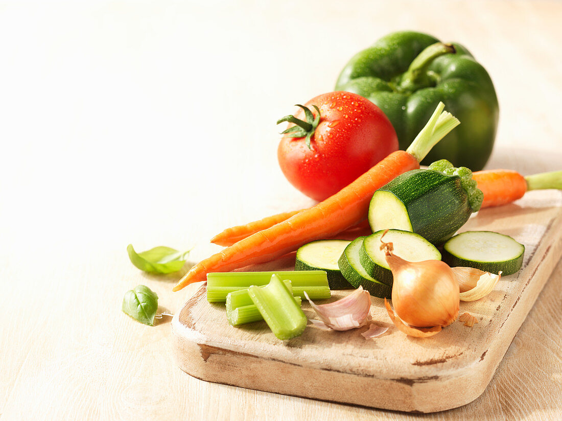 Fresh vegetables, partly sliced, on a chopping board