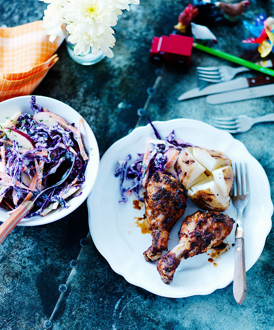 Grilled chicken drumsticks with a baked potato and red cabbage salad