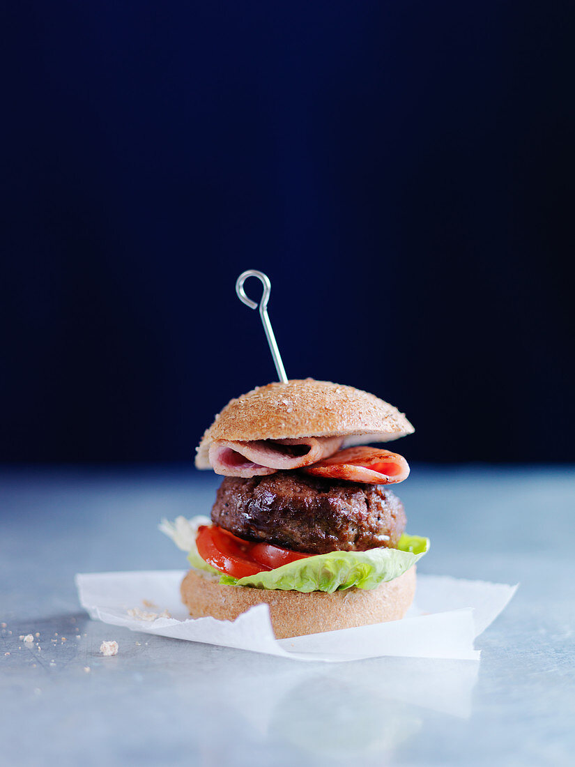 A burger with bacon, tomatoes and salad