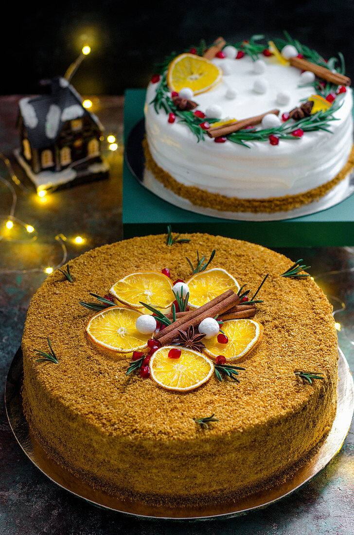 Two different Christmas cakes with oranges and cinnamon sticks